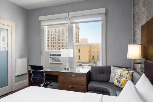 a bedroom with a desk and a couch and a window at Cartwright Hotel Union Square - BW Premier Collection in San Francisco