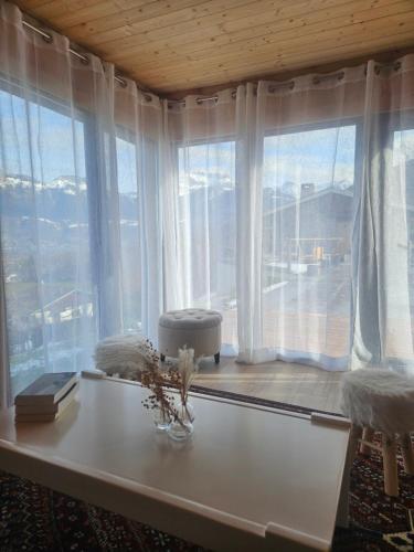 a living room with a table and large windows at Le Petit Chalet in Saint-Jorioz