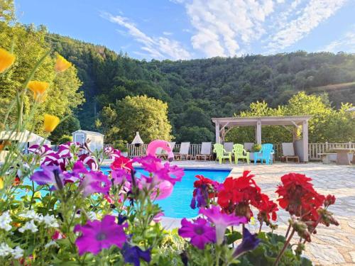 une piscine avec des fleurs et un kiosque dans l'établissement La Vallée, à Lacrouzette