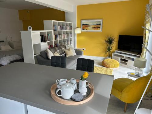 a living room with a table and a living room with yellow walls at The Studio in Dunfermline
