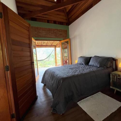 a bedroom with a bed in a room with a door at Chalé Bem-te-vi Vista espetacular da Serra da Mantiqueira in São José dos Campos