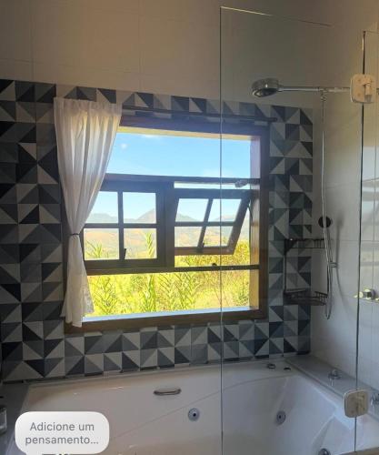 a bathroom with a window and a bath tub at Chalé Bem-te-vi Vista espetacular da Serra da Mantiqueira in São José dos Campos