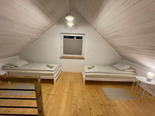 a attic room with two beds and a window at Bieszczadzkie Pola in Wańkowa