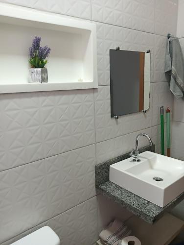 a bathroom with a white sink and a mirror at Kitnets bem localizada, próx ao autódromo! in Londrina