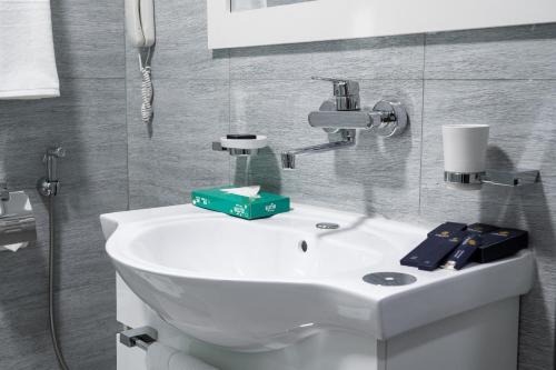 a bathroom with a white sink and a mirror at Rauza Hotel Tashkent in Tashkent