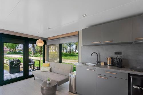 a kitchen and living room with a couch and a table at Houseboats Pean-buiten Weidum in Weidum