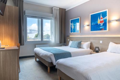a hotel room with two beds and a window at The Originals City, Hôtel Les Océanes, Lorient in Lorient
