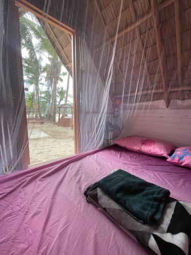 a bed in a tent with a pink blanket at Island Crib in El Nido