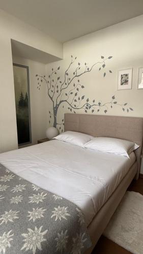 a bedroom with a bed with a tree on the wall at Maison Poluc - Maison Adeline in Champoluc