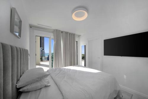 a white bedroom with a bed and a flat screen tv at Calpe Silver Tower 5B in Calpe