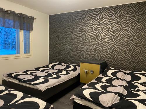 a bedroom with two beds and a patterned wall at Mökki unelmia in Jyväskylä