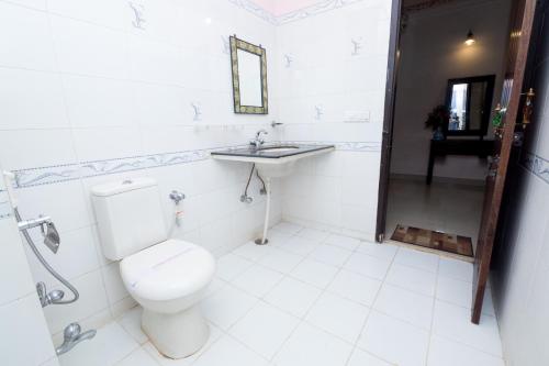 a white bathroom with a toilet and a sink at Hotel Moon Light Palace in Jaipur