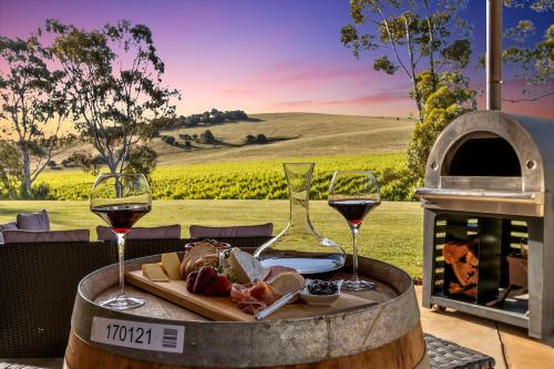 a table with two glasses of wine and a plate of food at Norm's Vineyard Retreat in Lyndoch