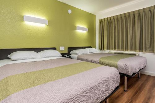 two beds in a room with green walls at Motel 6 Fort Worth, TX - North in Fort Worth