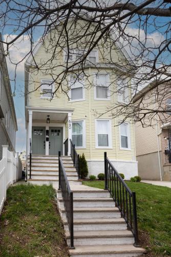 a yellow house with stairs in front of it at Excellence by Urooms Apartments Near NYC and Newark Airport with Parking in Elizabeth