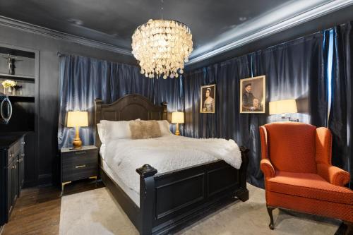 a bedroom with a bed and a chandelier and a chair at Spacious studio condo in historic Munger Place in Dallas