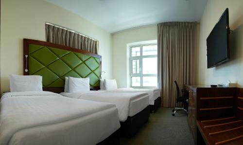 a hotel room with three beds and a television at Holyland Hotel Amman in Amman