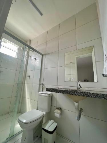 a white bathroom with a toilet and a mirror at Hotel Letiva Centro in Sobral