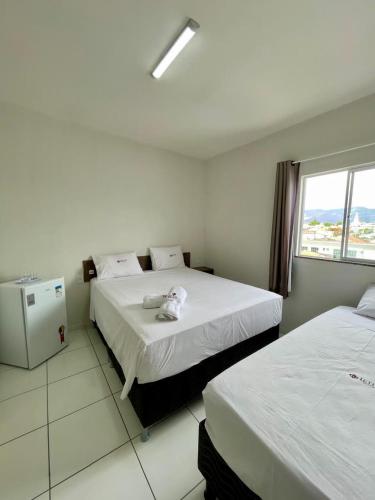 a hotel room with two beds and a window at Hotel Letiva Centro in Sobral