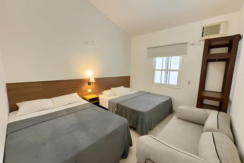 a hotel room with two beds and a couch at Studio VI até 7 pessoas em Juquehy in São Sebastião