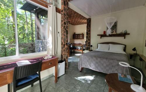 a bedroom with a bed and a desk and a window at Nature Lovers Quepos in Quepos