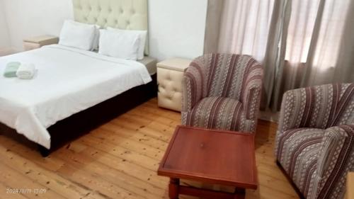 a hotel room with a bed and two chairs at Palm Terrace Guesthouse in Durban