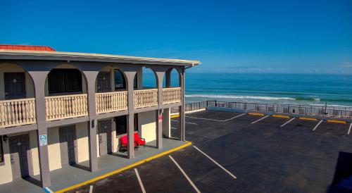 a building with a parking lot next to the ocean at La Bella Inn - POOL OPEN in Daytona Beach