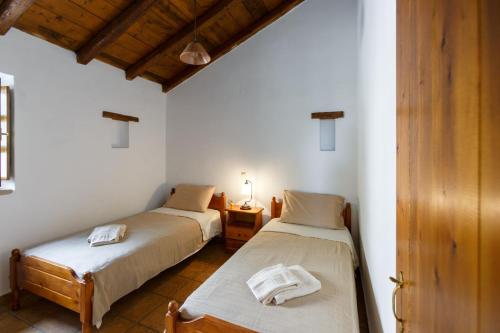 two beds in a room with white walls and wooden ceilings at Tzokeika Traditional Settlement in Riglia