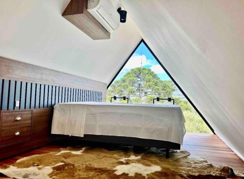 a bedroom with a large bed with a large window at Chalé da Árvore in Urubici
