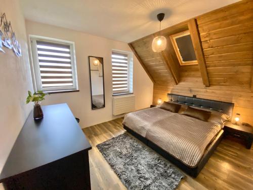 a bedroom with a bed and a table and windows at Psí bouda Benecko in Benecko