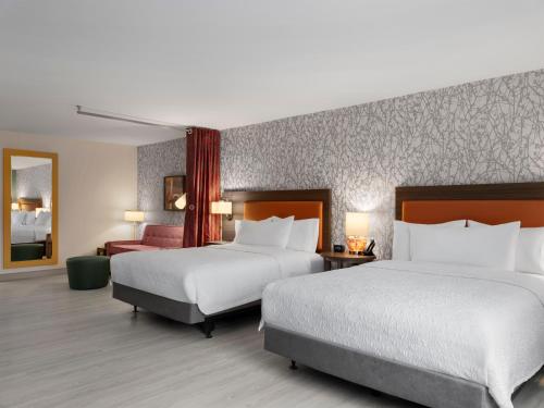 a hotel room with two beds and a chair at Tru By Hilton Norwalk Des Moines in Norwalk
