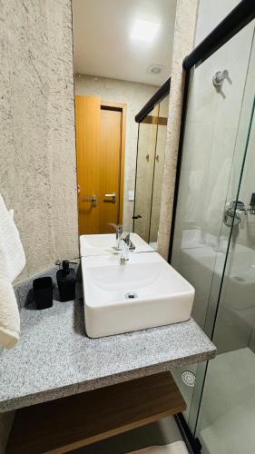 a bathroom with a white sink and a shower at Sunset Villas Milagres - Casa Anahi in Passo de Camarajibe