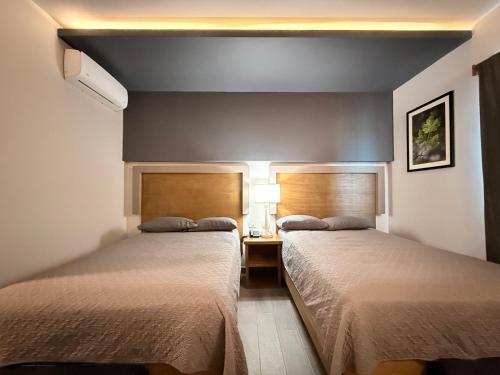 a bedroom with two beds and a table with a lamp at Hotel Los Diamantes in Rancho Los Limones