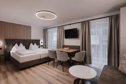 a hotel room with a bed and a table and chairs at Appartement Sport Steger in Saalbach-Hinterglemm