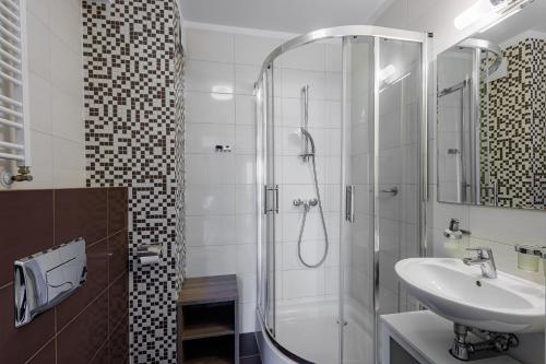a white bathroom with a shower and a sink at Apartamenty Baltic Horst Basen & Restauracja in Niechorze