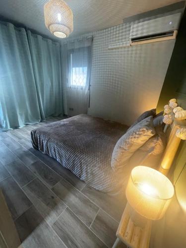 a bedroom with a bed and a lamp in it at Estrella, véritable havre de paix climatisé avec spa in Sainte-Marie