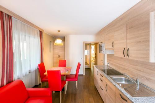 kuchnia z czerwonymi krzesłami i stołem w obiekcie Apartments Diamant w mieście Ortisei
