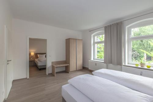 a white bedroom with two beds and a bathroom at Ferienapartments Pirna in Pirna