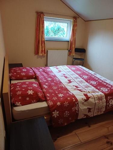 a bedroom with a bed with a red comforter and a window at Gîte de la barrière in Libin