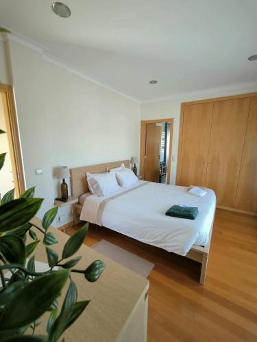 a bedroom with a large white bed and a plant at Casa da Calçada in Mujães