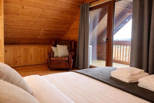 a bedroom with a bed and a chair and a window at Chalet O Refúgio 1 in Penhas da Saúde
