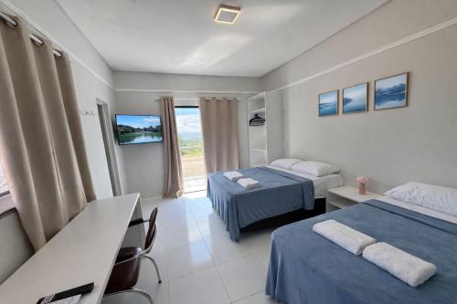 a hotel room with two beds and a television at Pousada do Horto in Juazeiro do Norte
