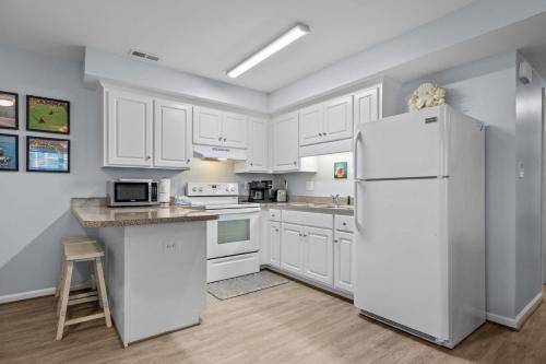 a kitchen with white cabinets and a refrigerator at Boardwalk Shores D in Atlantic Beach