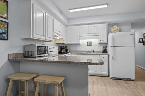 a kitchen with white cabinets and a white refrigerator at Boardwalk Shores D in Atlantic Beach