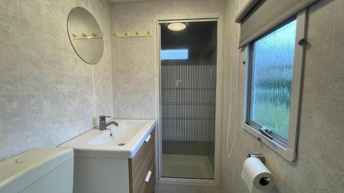 a white bathroom with a sink and a mirror at Retro Stacaravans in Warmond