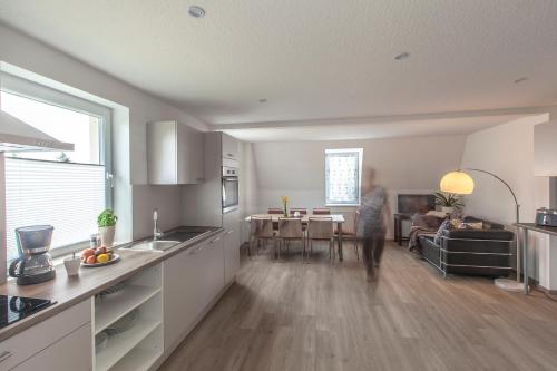 a kitchen and living room with a person standing in the kitchen at Ferienapartments Pirna in Pirna