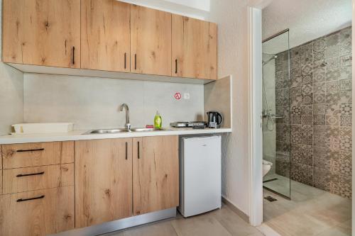 a kitchen with wooden cabinets and a sink and a shower at Lena Apartments in Elounda