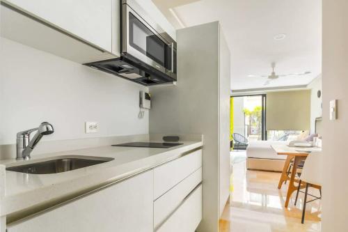 a white kitchen with a sink and a microwave at Central Studio - Rooftop Pool Gym Near Beach in Playa del Carmen