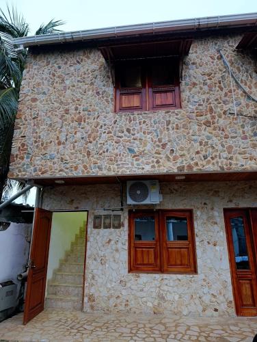 a stone house with wooden doors and a staircase at Glamar Apartamento in Arboletes