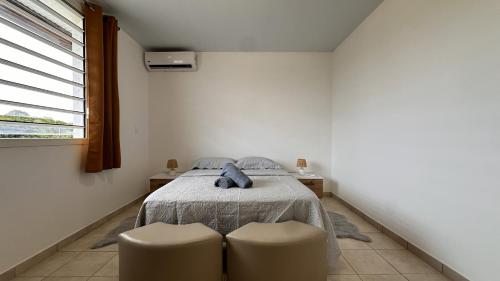 a bedroom with a bed with two chairs and a window at Vista - Route des plages - Destination Guyane in Rémire-Camp